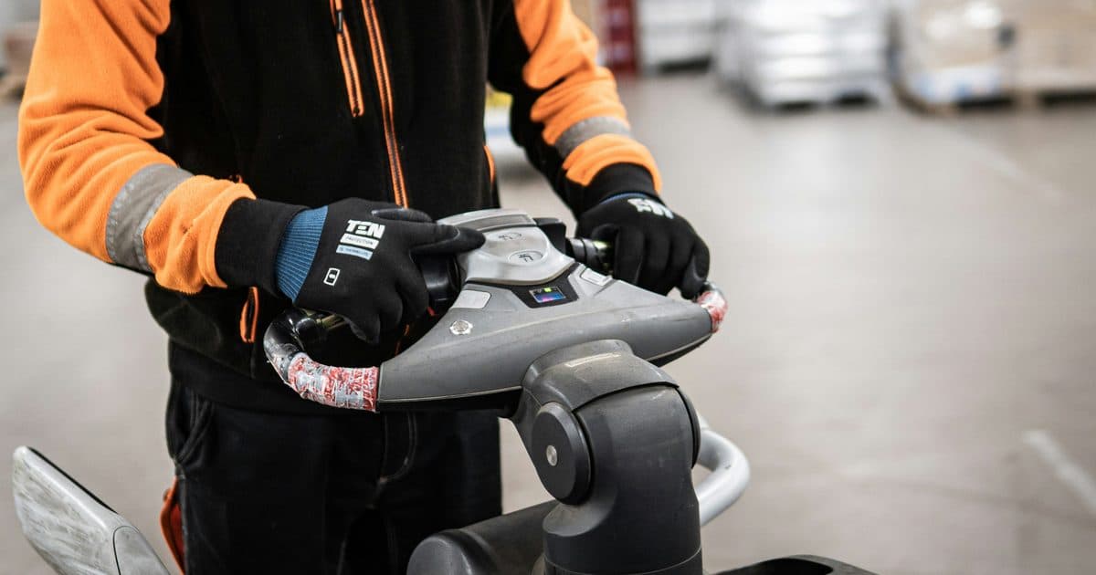 Warehouse worker operating a pallet jack to move equipment in a processing facility