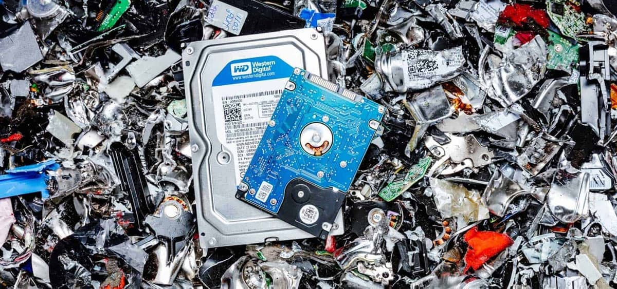 Physically destroyed hard drives alongside intact drives awaiting certified data sanitization